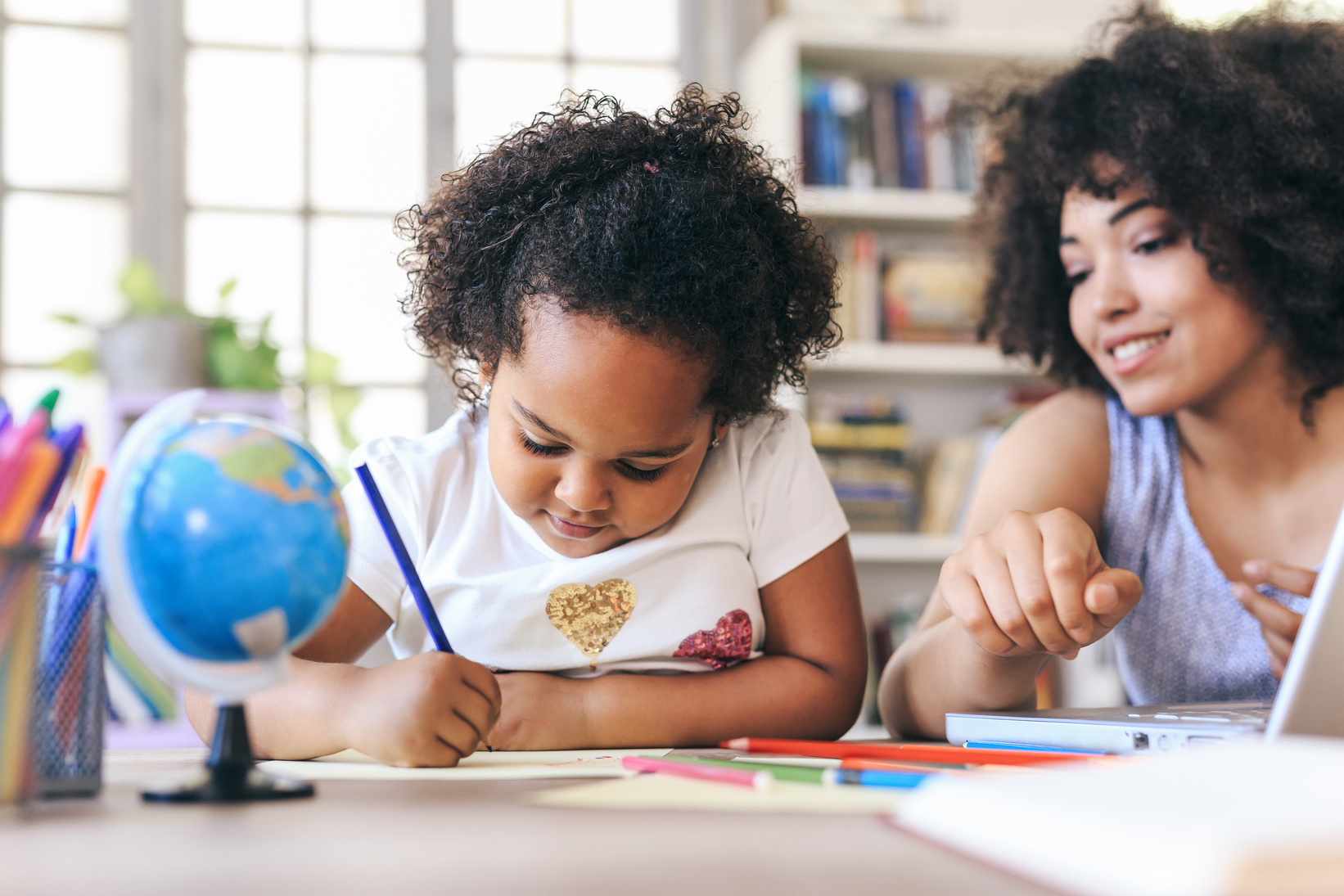 Child writing under parent's supervision